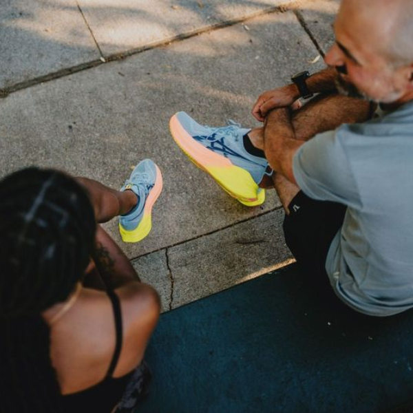 Two people sitting wearing ASICS shoes