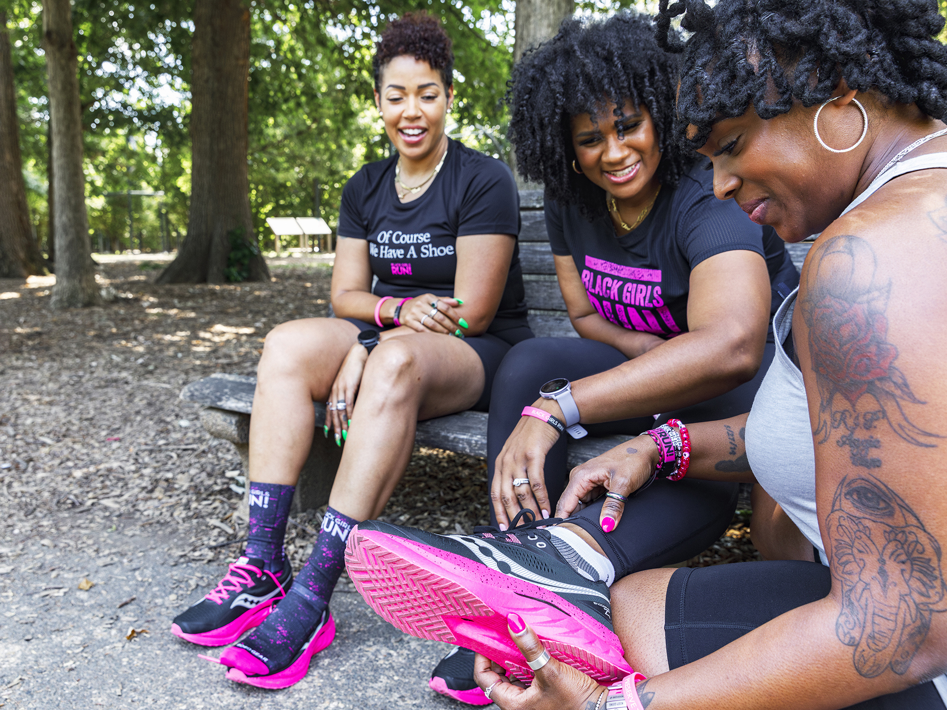 Three women sitting in the park looking at shoes